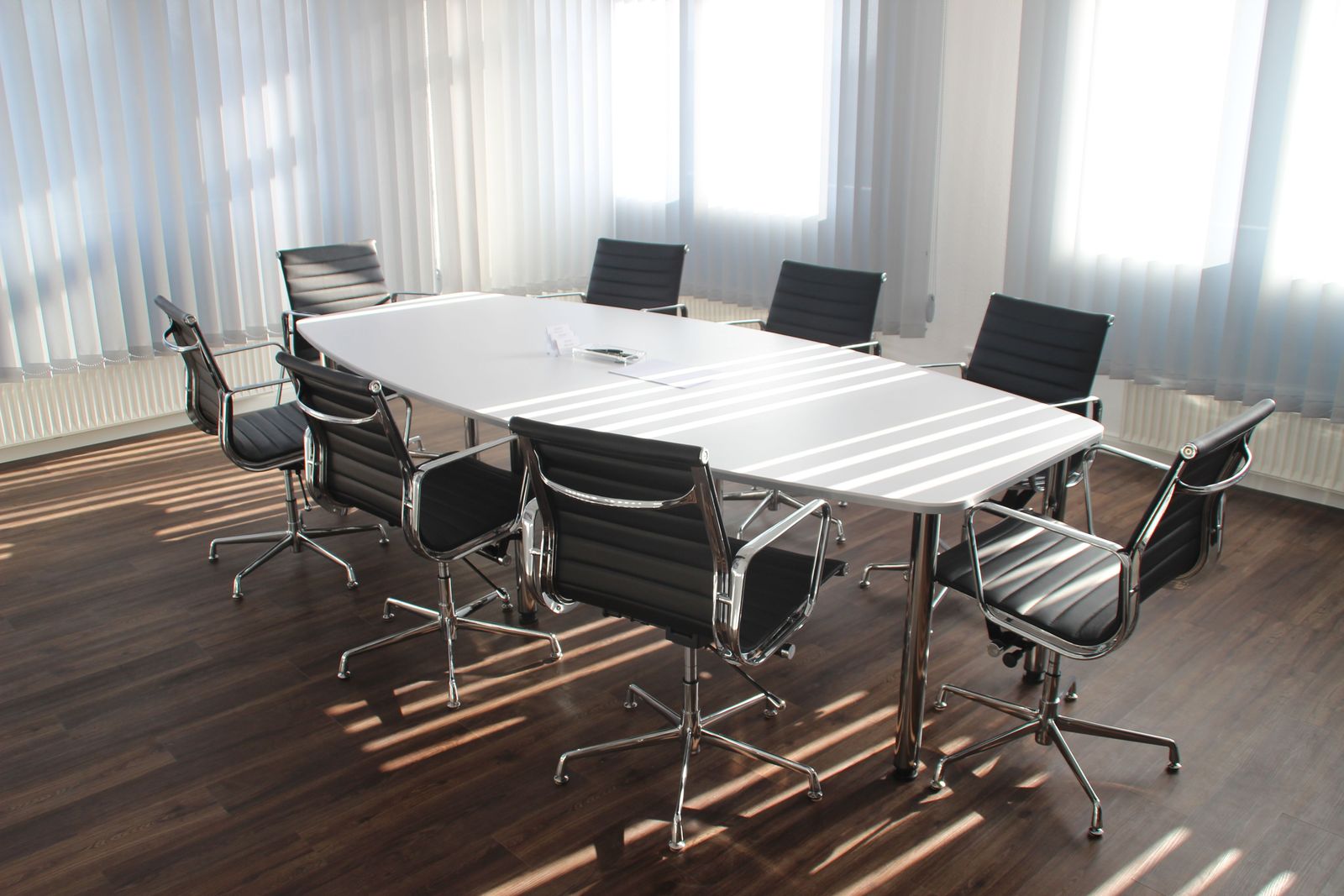 Sunlit boardroom with a long table and leather chairs